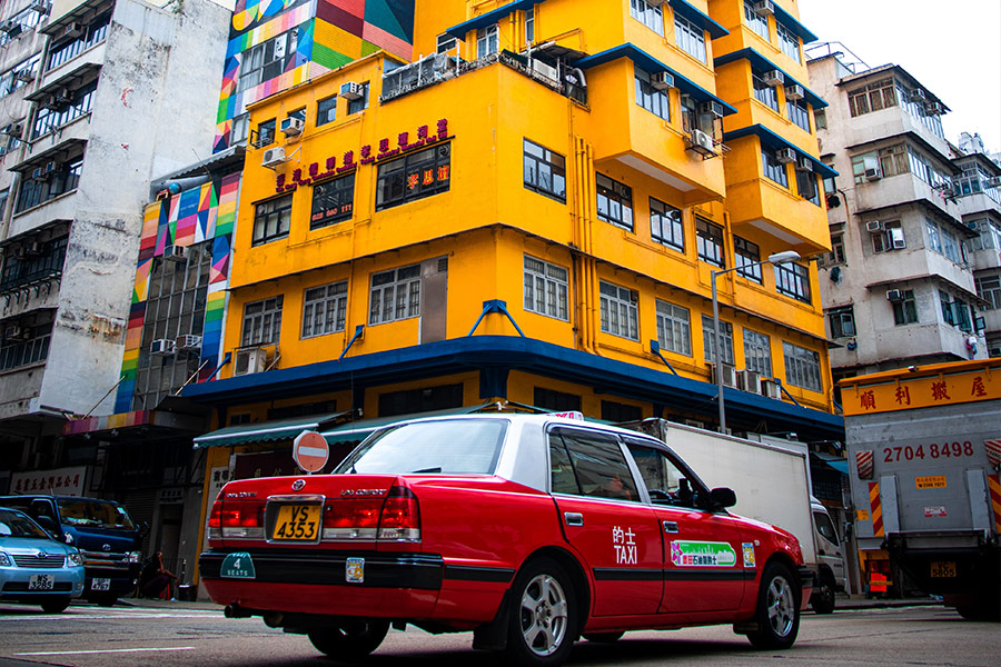 Red taxi passing classic yellow old building Hongkong