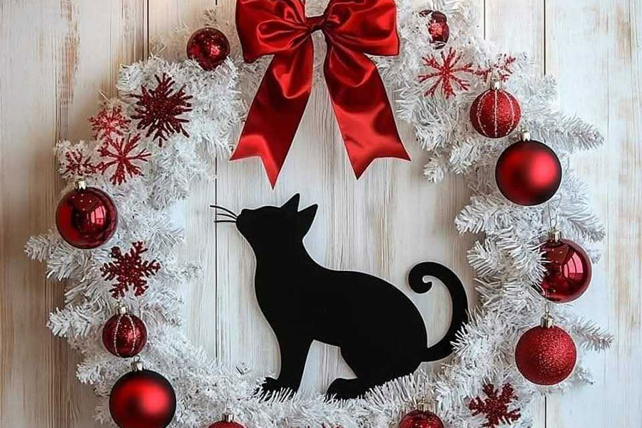 White Christmas wreath decorated with red ornaments and black cat