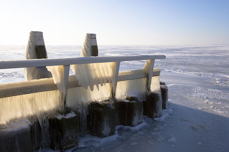 Icicles hang from a pier over frozen water