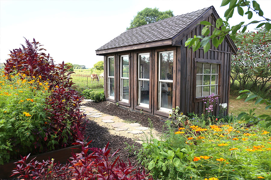 Old wooden gazebo in lush rural cottage garden