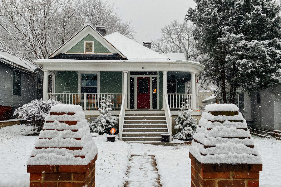 Snow covered wooden house near trees