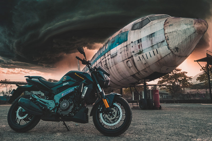 Dark green motocycle parked next old airplane