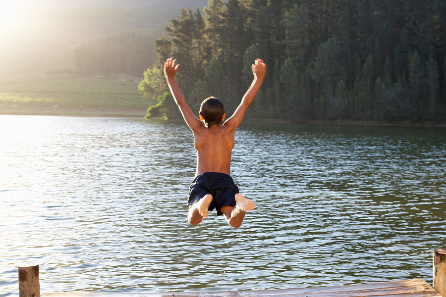 Young boy jumping into lake