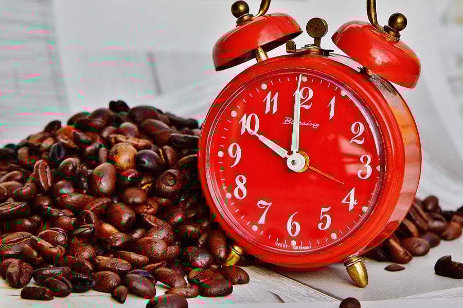 Pile of coffee beans next to bussing alarm clock