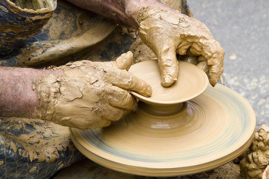 Alfarero dando forma a un objeto de arcilla.