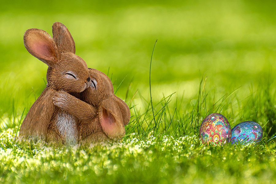 Coniglietto abbracciato in natura con uova colorate di Pasqua