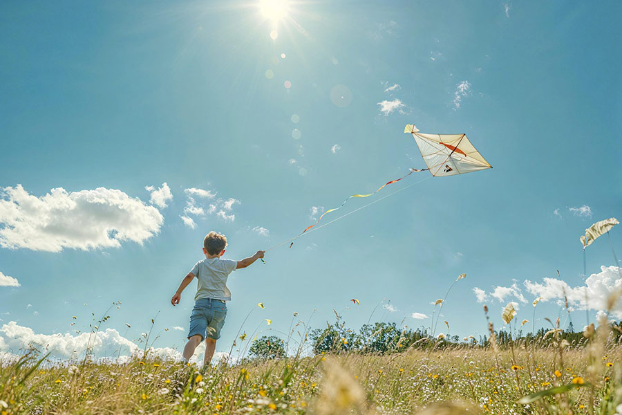 Bambino nel campo che fa volare un aquilone