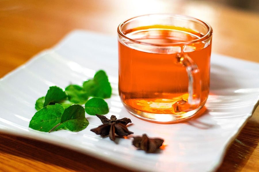 Vaso de té transparente con té de color marrón anaranjado.