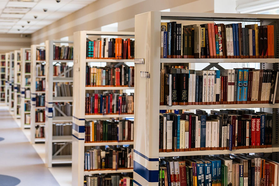 Biblioteca moderna con filas de altas estanterías blancas.