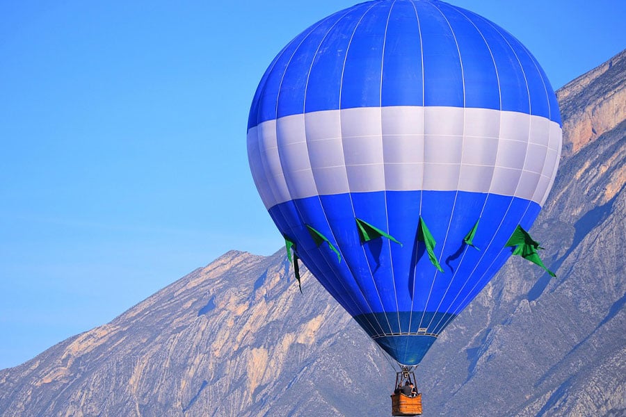 Globo aerostático azul y blanco con banderas verdes