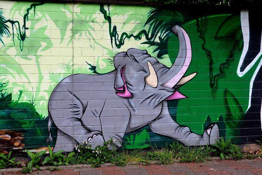 El mural muestra un elefante gris en un entorno selvático verde.