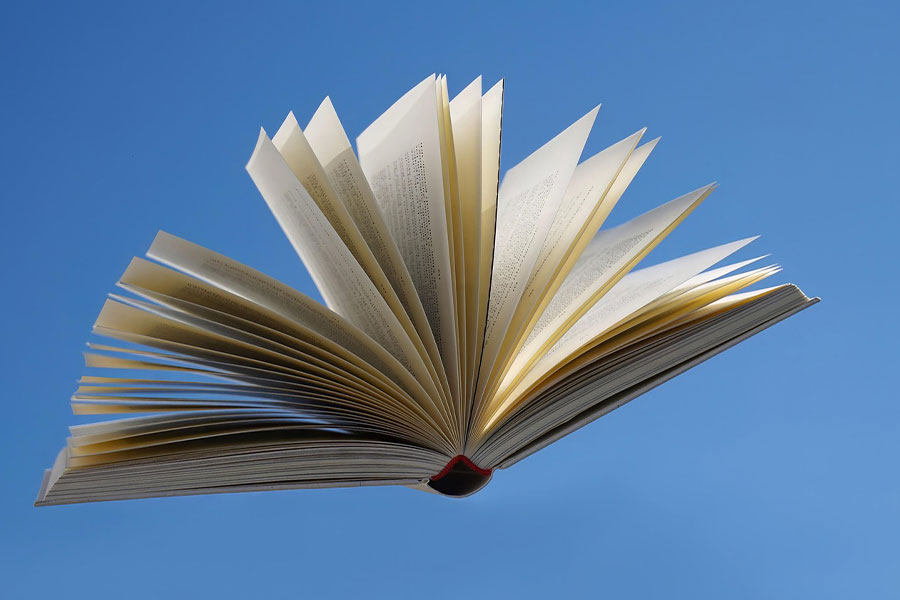 Libro abierto flotando contra un cielo azul claro