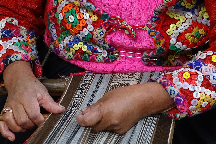 Mujer peruana tejiendo textiles tradicionales.