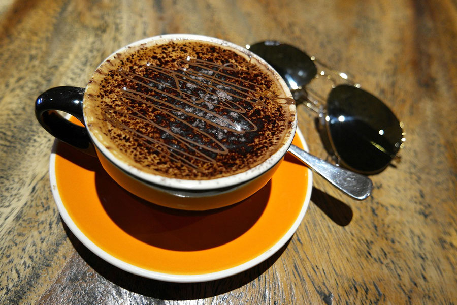 Deliciosa taza de café espolvoreada con cacao en polvo.