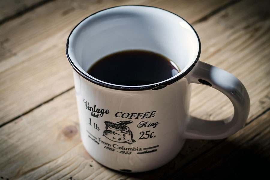 Café negro en taza con etiqueta vintage.