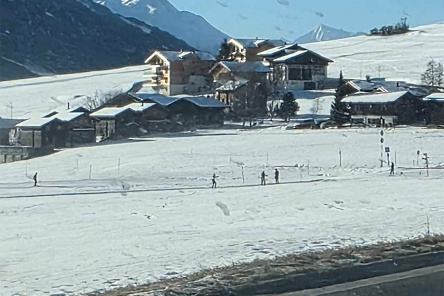 Paisaje de montaña cubierto de nieve con varios edificios de estilo chalet
