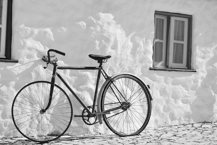 Bicicleta vintage monocromática apoyada en la pared blanca