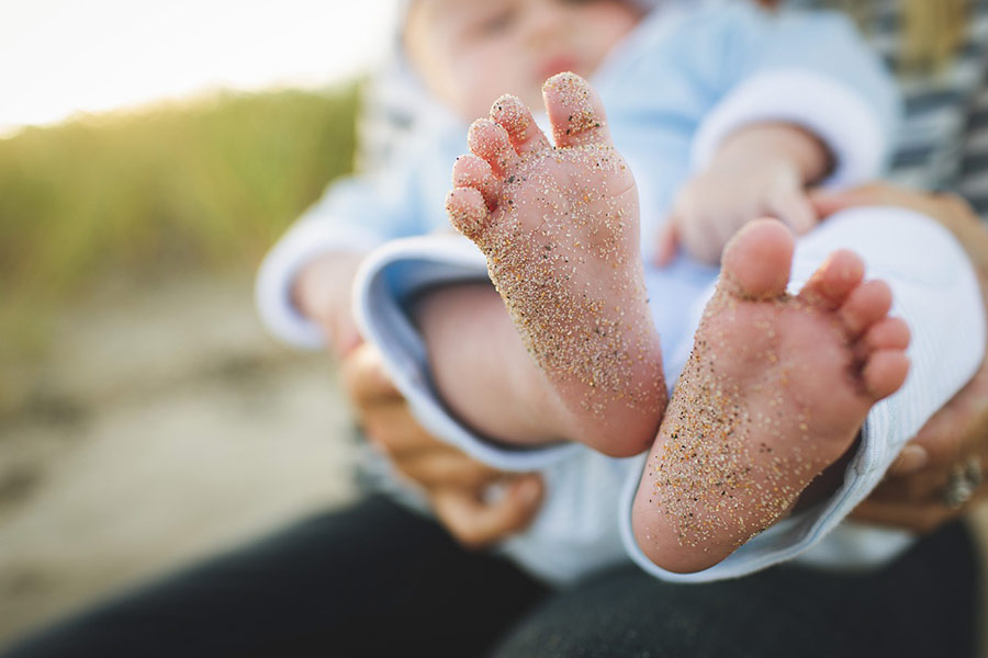 Säuglingsbabyfuß mit Sand